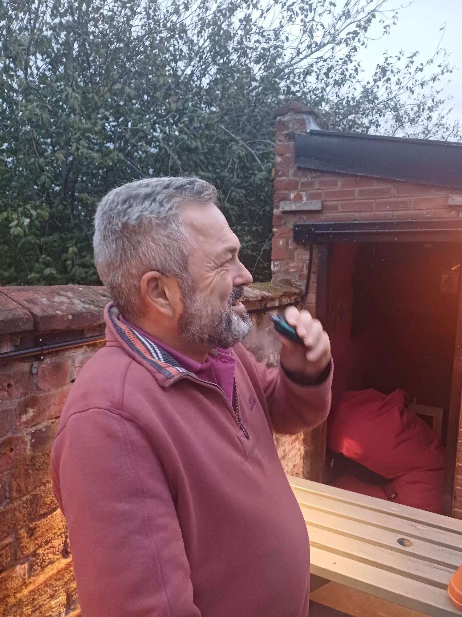 Homem de meia-idade usa cigarro eletrônico do lado de fora de um bar.