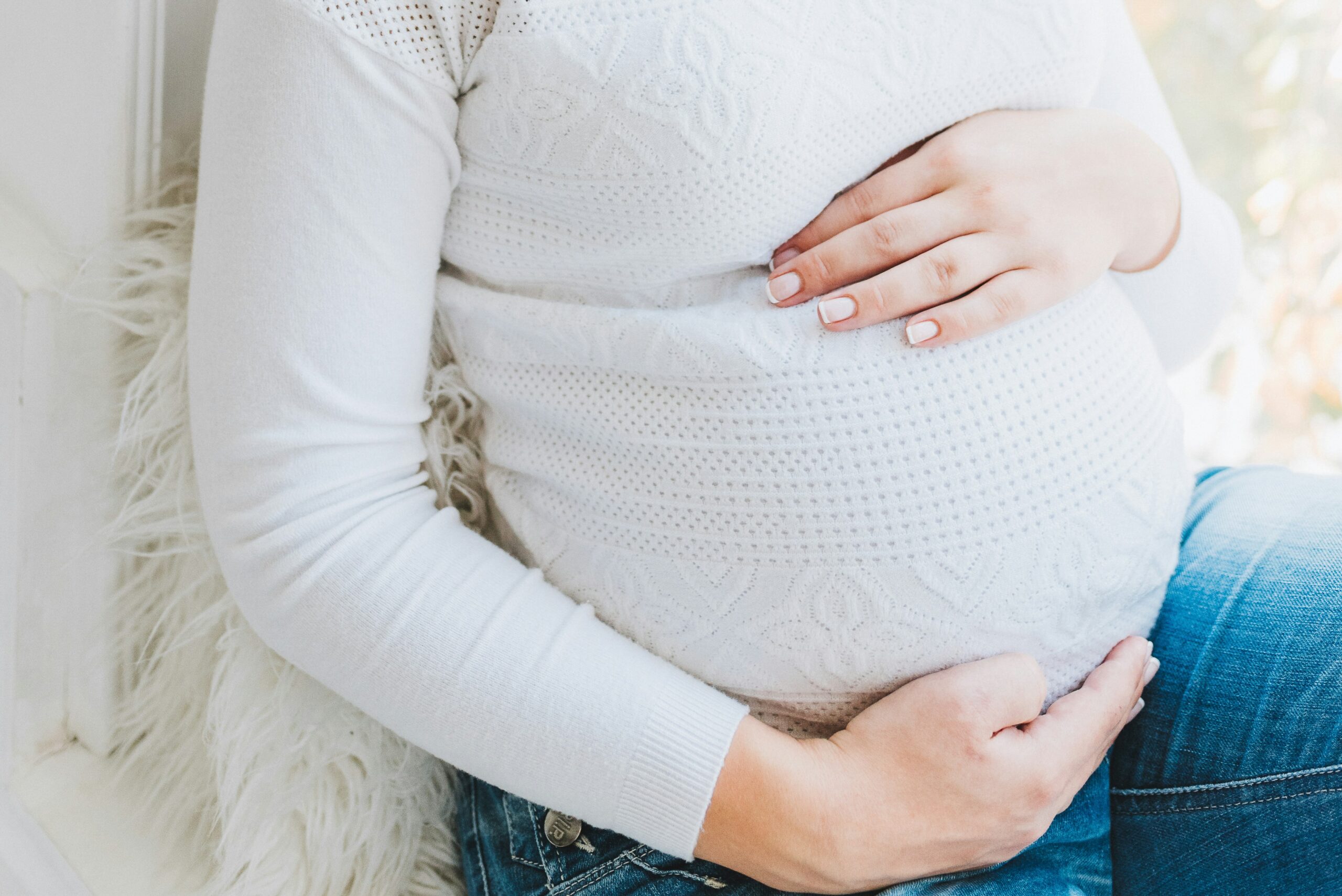 photo of a pregnant person in a white jumper - Photo by Anastasiia Chepinska on Unsplash